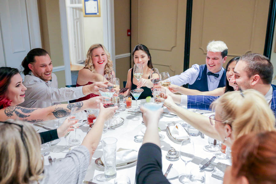 Colleagues toast a business cheer around a round table during a corporate holiday party at Le Cordon Bleu Ottawa.