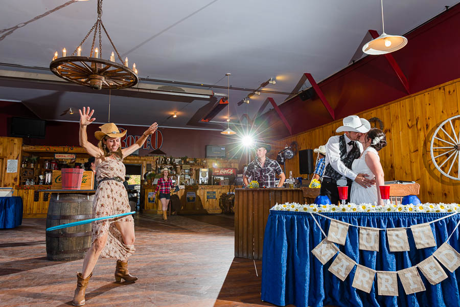 A lady in a stetson hula hoops to keep a bride and groom kissing game at Lone Star Ranch & Catering.