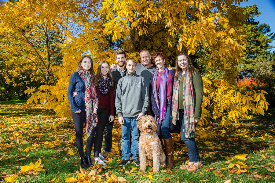 Kristen posing with her family during an outdoor photo shoot at the arboretum in autumn.